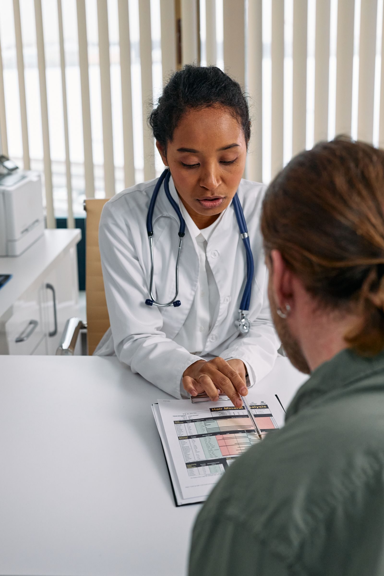 Une médecin explique un document à une personne assise en face d'elle, dans un cabinet